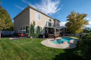 Back of property with a patio, a fenced in pool, a pergola, and a lawn