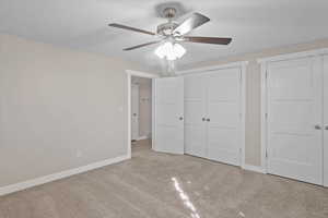 Unfurnished bedroom with a textured ceiling, light colored carpet, and ceiling fan