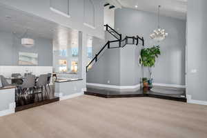 Interior space featuring carpet floors, high vaulted ceiling, and a notable chandelier