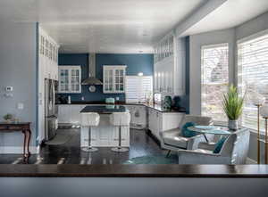 Kitchen featuring pendant lighting, white cabinets, wall chimney exhaust hood, dark hardwood / wood-style flooring, and stainless steel appliances