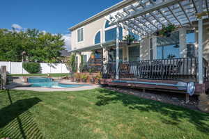 Rear view of property featuring ceiling fan, a fenced in pool, a pergola, and a yard