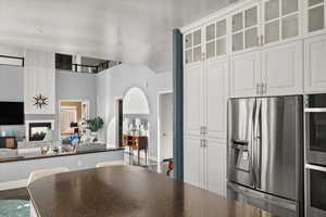 Kitchen featuring a multi sided fireplace, white cabinetry, and appliances with stainless steel finishes