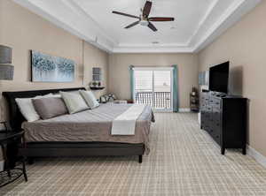 Carpeted bedroom with a raised ceiling, access to exterior, and ceiling fan