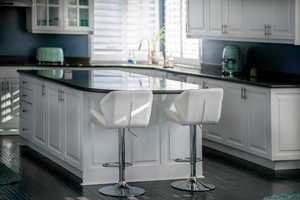 Kitchen featuring a breakfast bar area, white cabinets, dark hardwood / wood-style floors, and a kitchen island