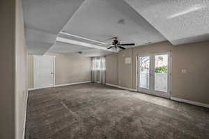 Carpeted empty room with plenty of natural light, ceiling fan, a textured ceiling, and french doors