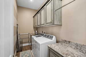 Clothes washing area with dark hardwood / wood-style floors, cabinets, and separate washer and dryer