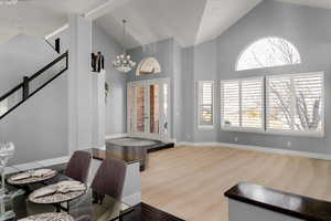 Carpeted dining room featuring high vaulted ceiling, a healthy amount of sunlight, and a notable chandelier