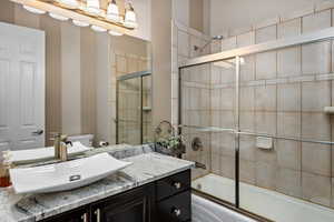 Full bathroom with combined bath / shower with glass door, vanity, and toilet