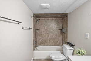 Full bathroom featuring vanity, a textured ceiling, toilet, and tiled shower / bath