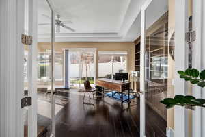 Office featuring dark hardwood / wood-style floors, ceiling fan, a raised ceiling, and french doors