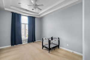 Interior space featuring a raised ceiling and ceiling fan