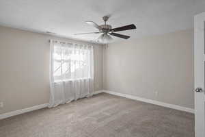 Spare room with ceiling fan, carpet floors, and a textured ceiling