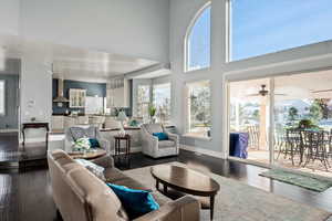 Living room with a high ceiling, dark hardwood / wood-style flooring, and ceiling fan