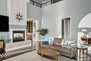 Living room featuring a multi sided fireplace, wood-type flooring, and a high ceiling