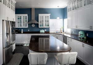 Kitchen with white cabinetry, stainless steel appliances, and wall chimney range hood