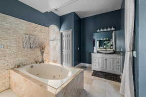 Bathroom with vanity and tiled bath