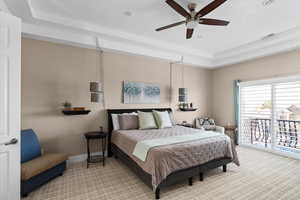 Bedroom with carpet, ceiling fan, access to exterior, and a tray ceiling