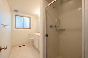 Bathroom with tile patterned floors, toilet, an enclosed shower, and vanity