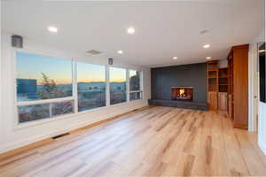 Unfurnished living room with light wood-type flooring and a brick fireplace