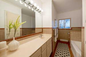 Bathroom with tile patterned flooring, vanity, tile walls, and a baseboard radiator