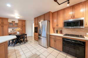 Kitchen featuring backsplash, light tile patterned flooring, and appliances with stainless steel finishes