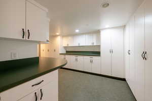 Kitchen featuring dark colored carpet and white cabinetry