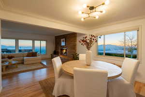 Dining room with a mountain view, a chandelier, light hardwood / wood-style floors, a fireplace, and ornamental molding