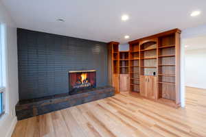 Unfurnished living room featuring light wood-type flooring and a tiled fireplace