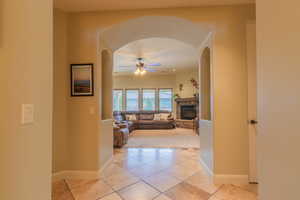 Tiled great room featuring a stone fireplace & ceiling fan