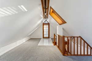 Bonus room with lofted ceiling with skylight and light carpet