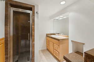 Bathroom featuring tile patterned floors, vanity, and a shower with shower door