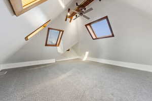 Bonus room featuring carpet, lofted ceiling with skylight, and ceiling fan