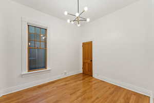 Unfurnished room with wood-type flooring and a notable chandelier