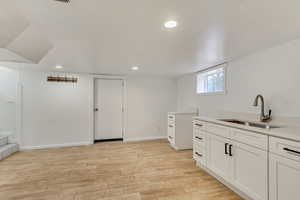 Kitchen featuring sink, white cabinets, and light wood-type flooring