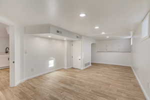 Basement with sink and light hardwood / wood-style flooring