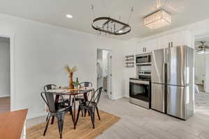 Kitchen with white cabinets, ceiling fan with notable chandelier, light hardwood / wood-style floors, and appliances with stainless steel finishes