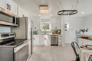 Kitchen featuring white cabinets, stainless steel appliances, and sink