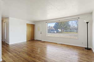 Empty room featuring wood-type flooring and a textured ceiling