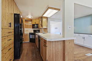 Kitchen featuring black appliances, white cabinets, sink, dark hardwood / wood-style floors, and kitchen peninsula