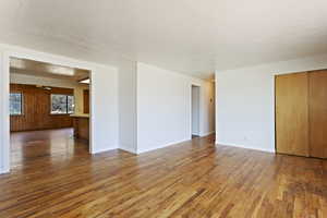 Empty room featuring hardwood / wood-style floors, a textured ceiling, ceiling fan, and wood walls