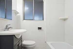 Full bathroom featuring vanity, tiled shower / bath combo, and toilet