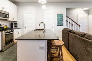 Kitchen with a kitchen island with sink, sink, stainless steel appliances, and light hardwood / wood-style flooring