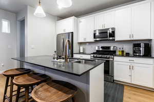 Kitchen with a center island with sink, white cabinetry, and stainless steel appliances