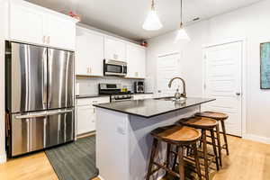 Kitchen with white cabinetry, a center island with sink, and appliances with stainless steel finishes