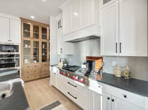 Kitchen featuring white cabinets, appliances with stainless steel finishes, tasteful backsplash, and light hardwood / wood-style flooring