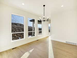 Unfurnished dining area featuring a chandelier and light hardwood / wood-style floors