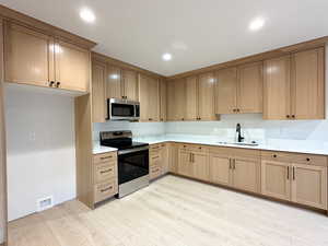 Kitchen with stainless steel appliances, light hardwood / wood-style floors, and sink