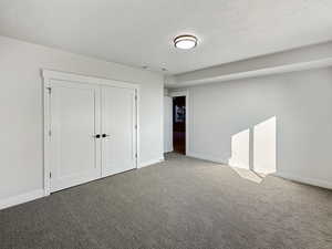 Unfurnished bedroom with a closet, carpet, and a textured ceiling