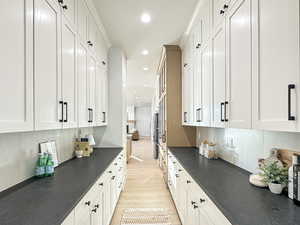 Kitchen featuring backsplash, light hardwood / wood-style flooring, and white cabinetry