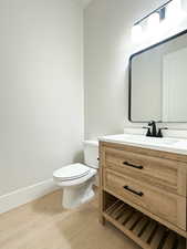 Bathroom featuring hardwood / wood-style floors, vanity, and toilet